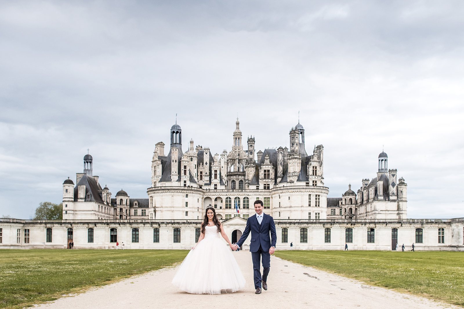 les mariés se tiennent devant le féérique château de chambord, château de la loire classé au patrimoine mondial de l'humanité